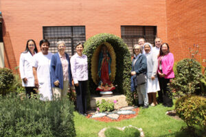 Autoridades del Gobierno General de Hermanas Hospitalarias y directivos de Clínica Nuestra Señora de Guadalupe posan junto a la estatua de la Virgen de Guadalupe.
